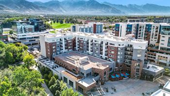 A large building complex with a courtyard in the foreground and mountains in the background.